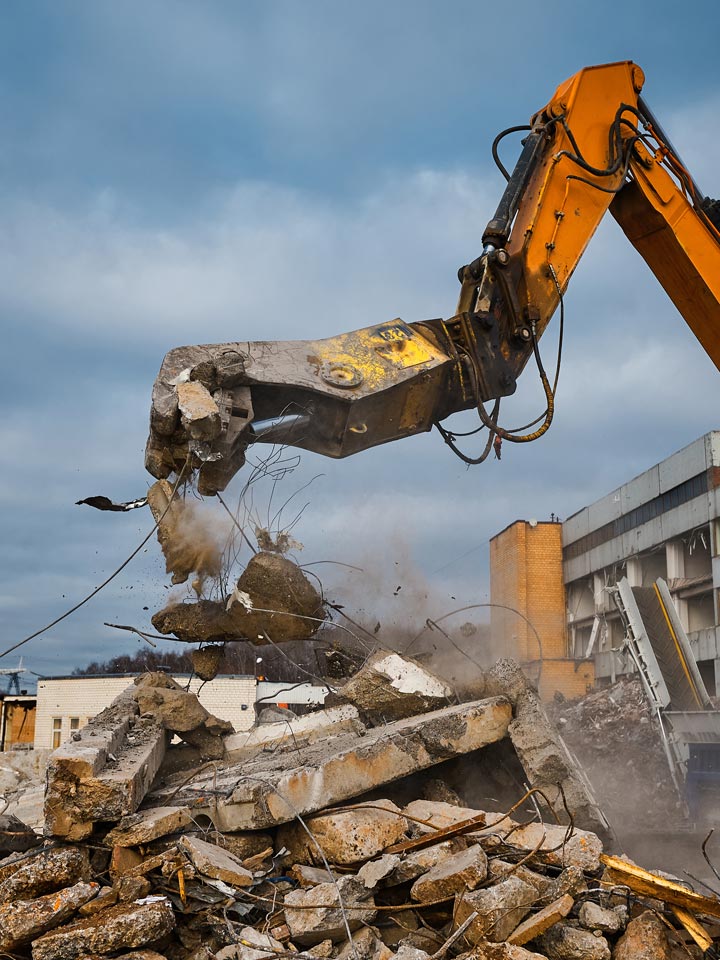 Excavator with hydraulic press breaks concrete leftovers